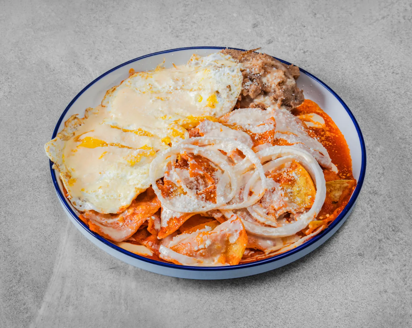 Chilaquiles rojos servidos con huevos y frijoles refritos