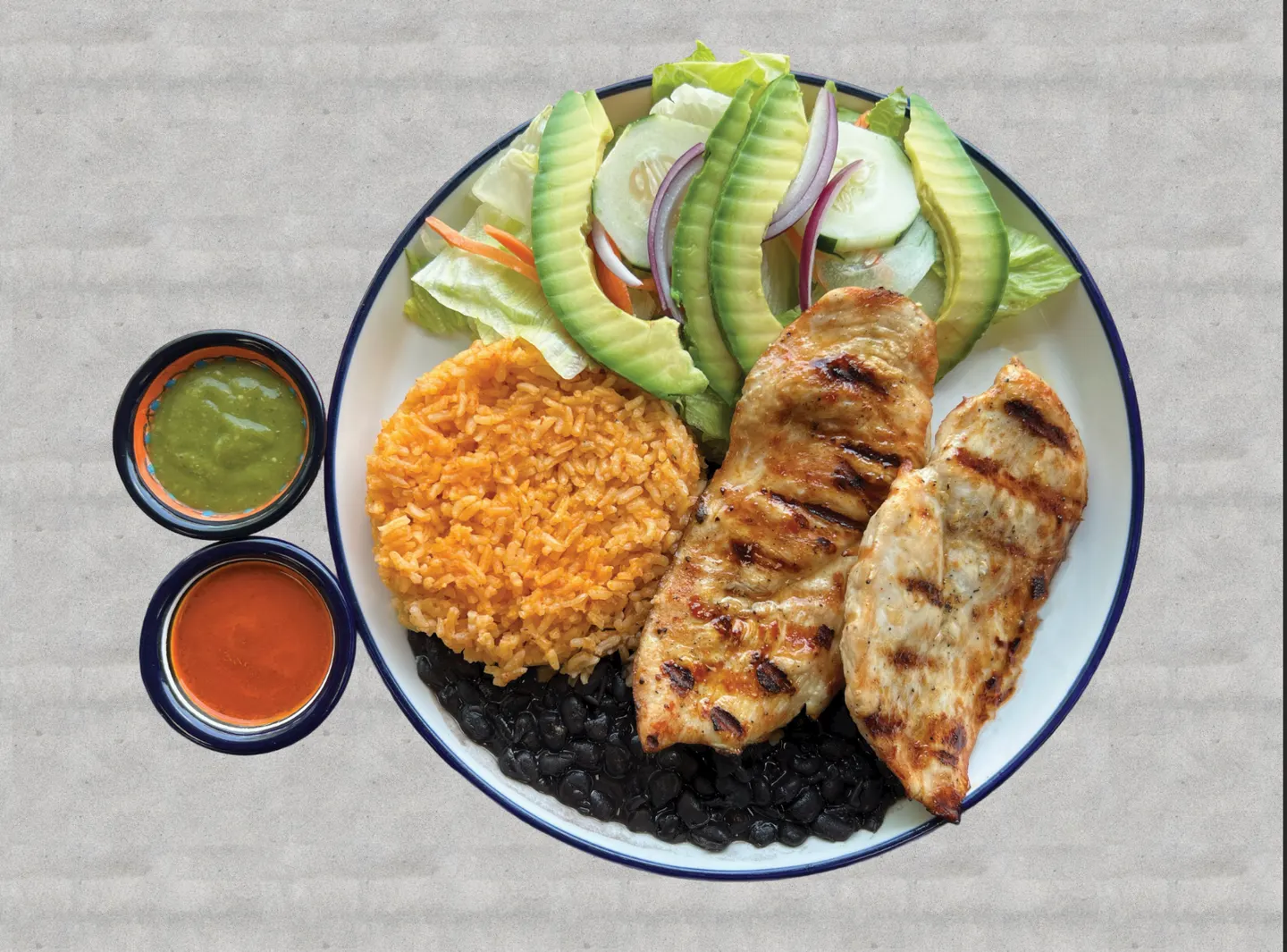 Plato de pollo a la parrilla con arroz, frijoles negros, ensalada, aguacate y salsa