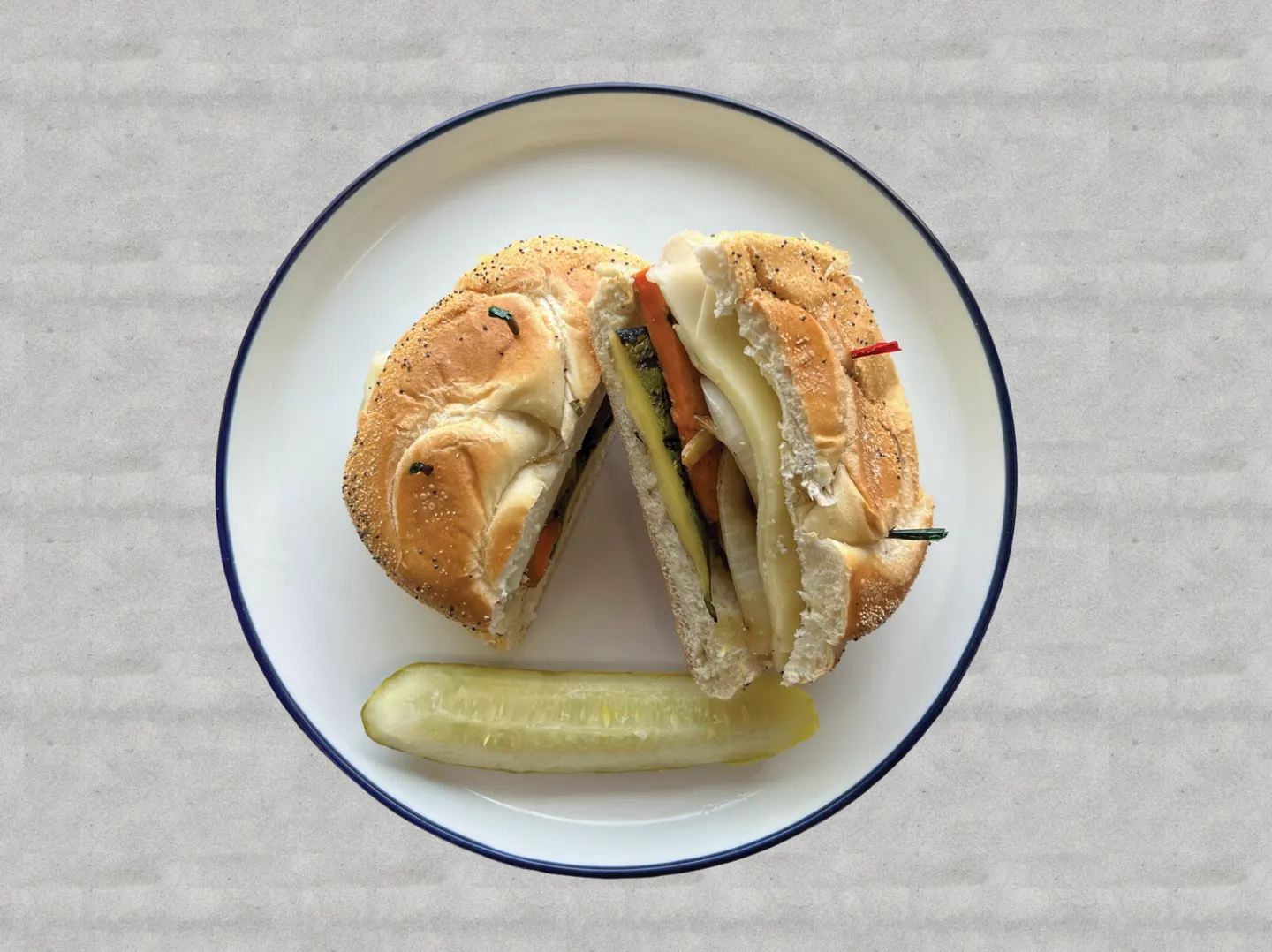 Sándwich de vegetales a la parrilla y queso servido con pepinillo