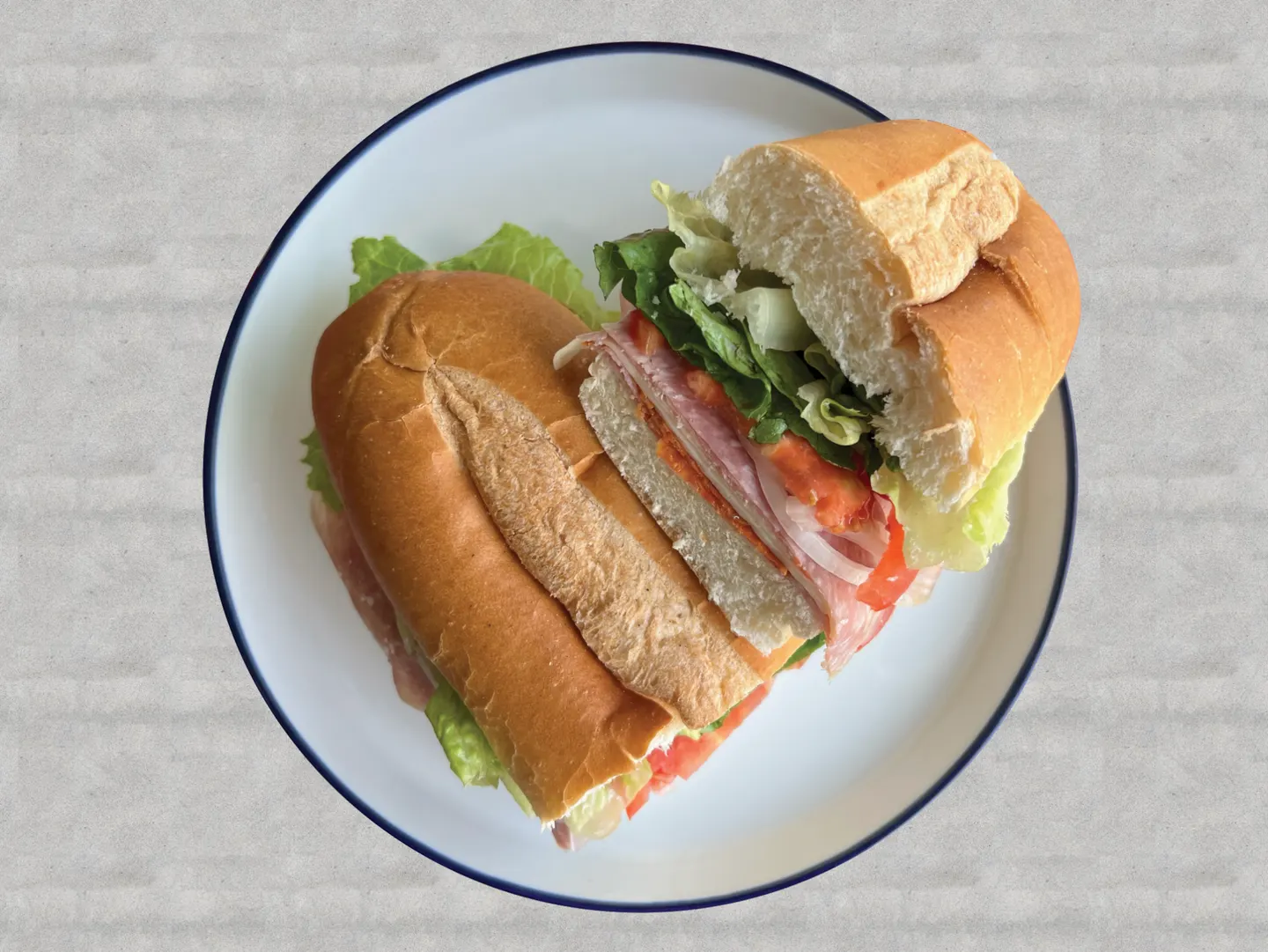 Sándwich italiano en pan hero con carnes frías, lechuga, tomate y cebolla